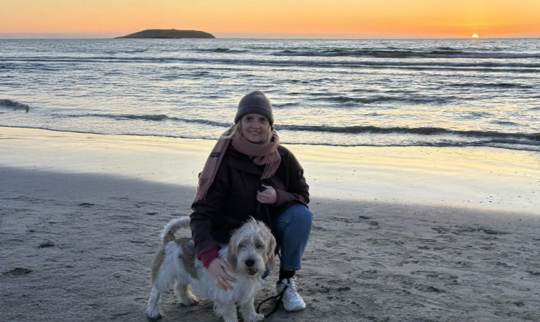 Astrid med hunden sin på stranden i solnedgang