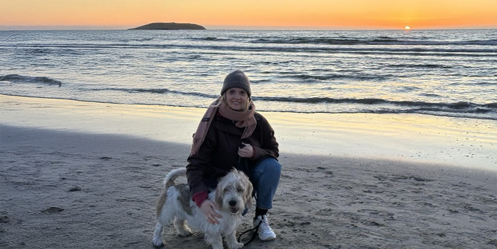 Astrid med hunden sin på stranden i solnedgang